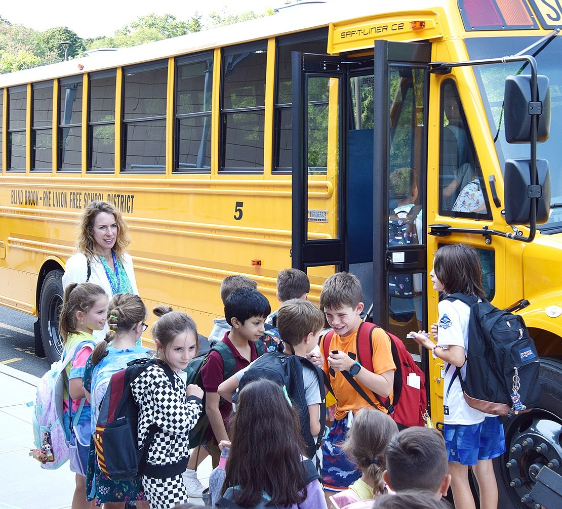 Caroline O’Brien, a teacher’s aide at Ridge Street School, ensures a group of students makes their way onto the proper bus safely.