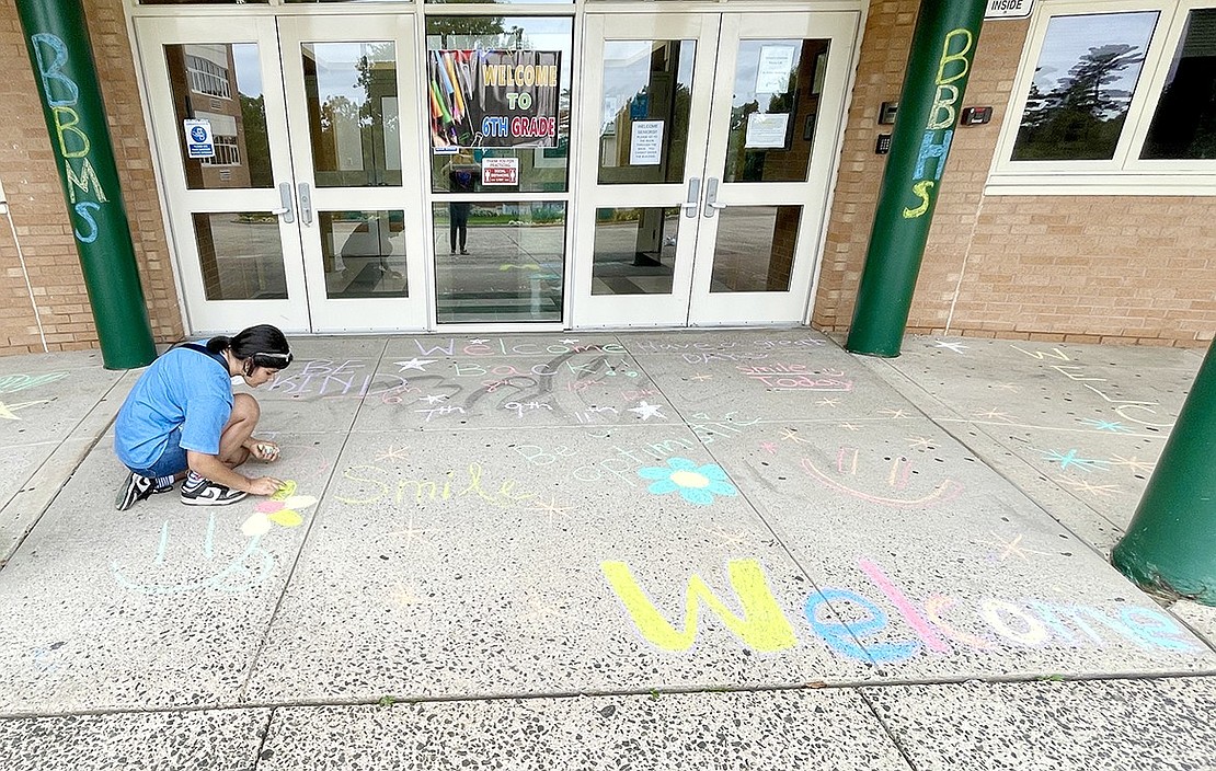 Talcott Road resident Anvitha Bhatt, a seventh-grader, adds a colorful flower to the entrance of Blind Brook Middle/High School during Chalk the Walk.