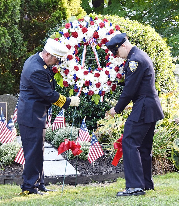 Port Chester Fire Department First Assistant Chief Angelo Sposta, Jr. (left) and Port Chester Police Detective Jared Pennella place a wreath in front of the 9/11 memorial in Lyon Park on the 23rd anniversary of the Sept. 11 terrorist attacks on Wednesday. Pennella’s father, Ronald, died last year after a battle with cancer, which developed due to his work at the World Trade Center site, where he spent 18 months as part of the initial recovery and cleanup crew following the attacks.