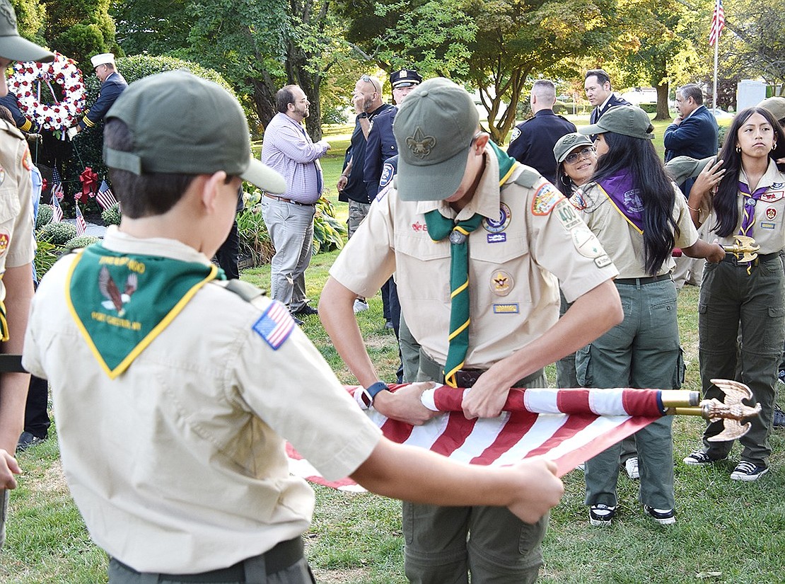 Port Chester BSA Troop 400 Scouts Peter Ayala (left) and Julian Cavallino work together to properly roll an American flag after the ceremony.