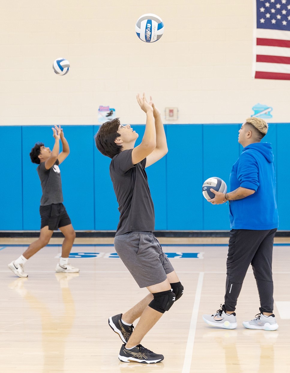 Coach Jhonattan Cortez supervises senior captain Gabriel Franco and junior Jake Vazquez doing a walking overhead passing drill during a practice session in the Port Chester High School gym before the boys’ volleyball season began.