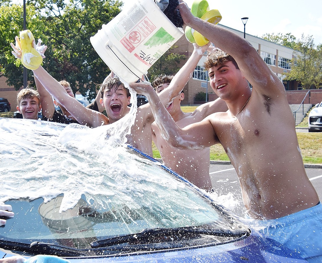 Blind Brook High School senior Tyler Taerstein dumps a bucket of soapy water onto a car while senior Chase Katz cheers along with a few other boys’ varsity soccer teammates on Saturday, Sept. 14. Hosting their annual car wash fundraiser, the squad collected $3,000 for Project ADAM, a program advocating for sudden cardiac arrest emergency preparedness in schools, and the Friends of Blind Brook Fund.