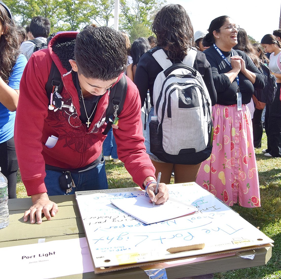 Senior Arturo Orozco of Highland Street signs up to join The Port Light. The school newspaper was one of the many clubs tabling at the event.