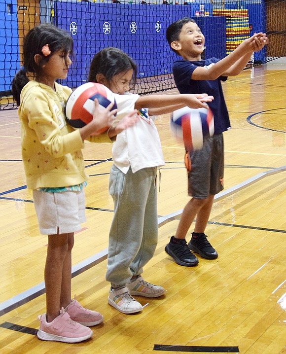 Ridge Street Elementary School third-graders Medha Madhu (left) and Nysa Agrawal, along with second-grader Manav Madhu, get fired up in their school gym during a volleyball clinic hosted by the Blind Brook varsity team on Tuesday, Sept. 24.