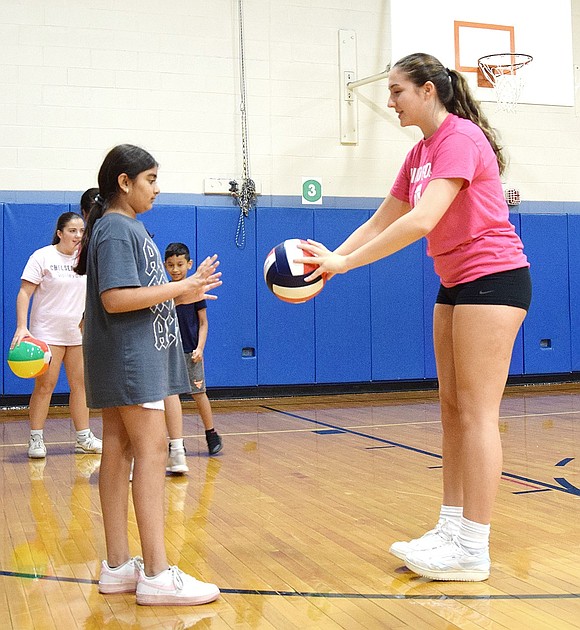 Reia Bhuva, a sixth-grade resident of Rockinghorse Trail, learns the ropes from senior varsity player Madeline Hirsch of Beacon Lane.