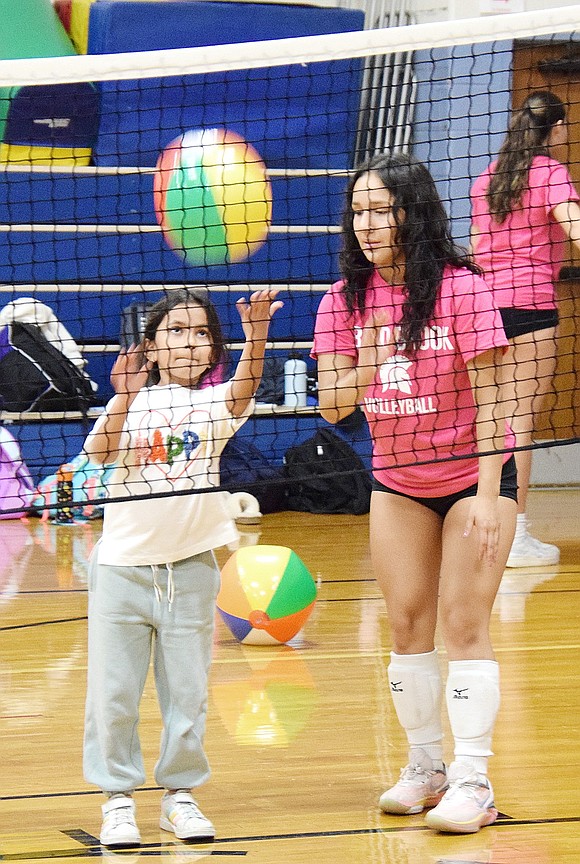 Nysa Agrawal, a third-grader, gets used to the volleyball movements by hitting an inflatable beach ball as senior Maria Gracia Leyva watches over her.