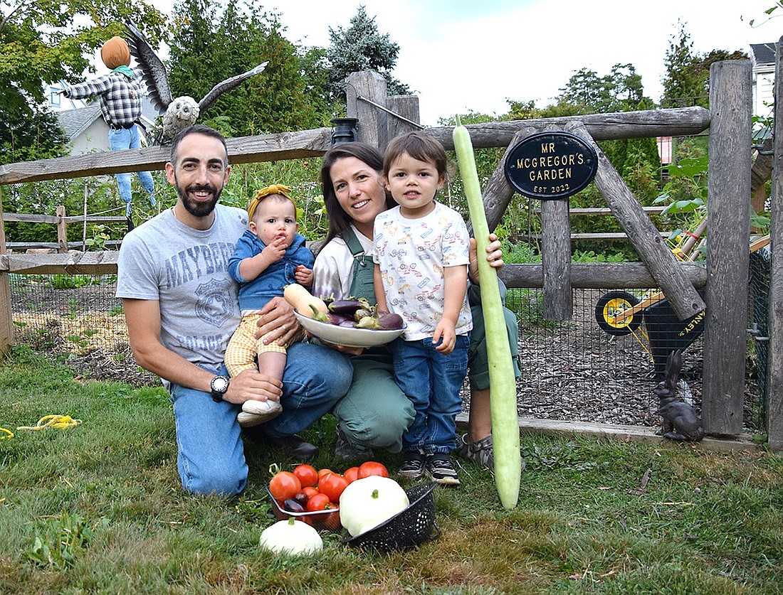 The Fragicomo family—Greg and Mary and their children John and Sophia—pose for a photo near the gate of the 30-by-30 garden plot in the backyard of their Indian Road home on Sept. 24. The family is slated to harvest over 600 pounds of fruits and vegetables this year.