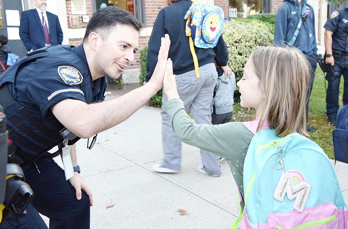 School Resource Officer Moises Ochoa gives College Avenue 5-year-old Maya Marollo a high five as she makes her way towards her kindergarten class at Park Avenue School.