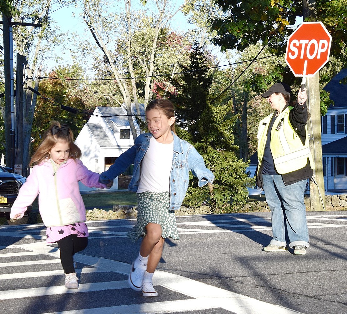 Giuliana Zanzano (left), 4, and Giada Lio, 6, rush across King Street towards their school building with some help from crossing guard Ami Lori during International Walk to School Day on Tuesday, Oct. 8.