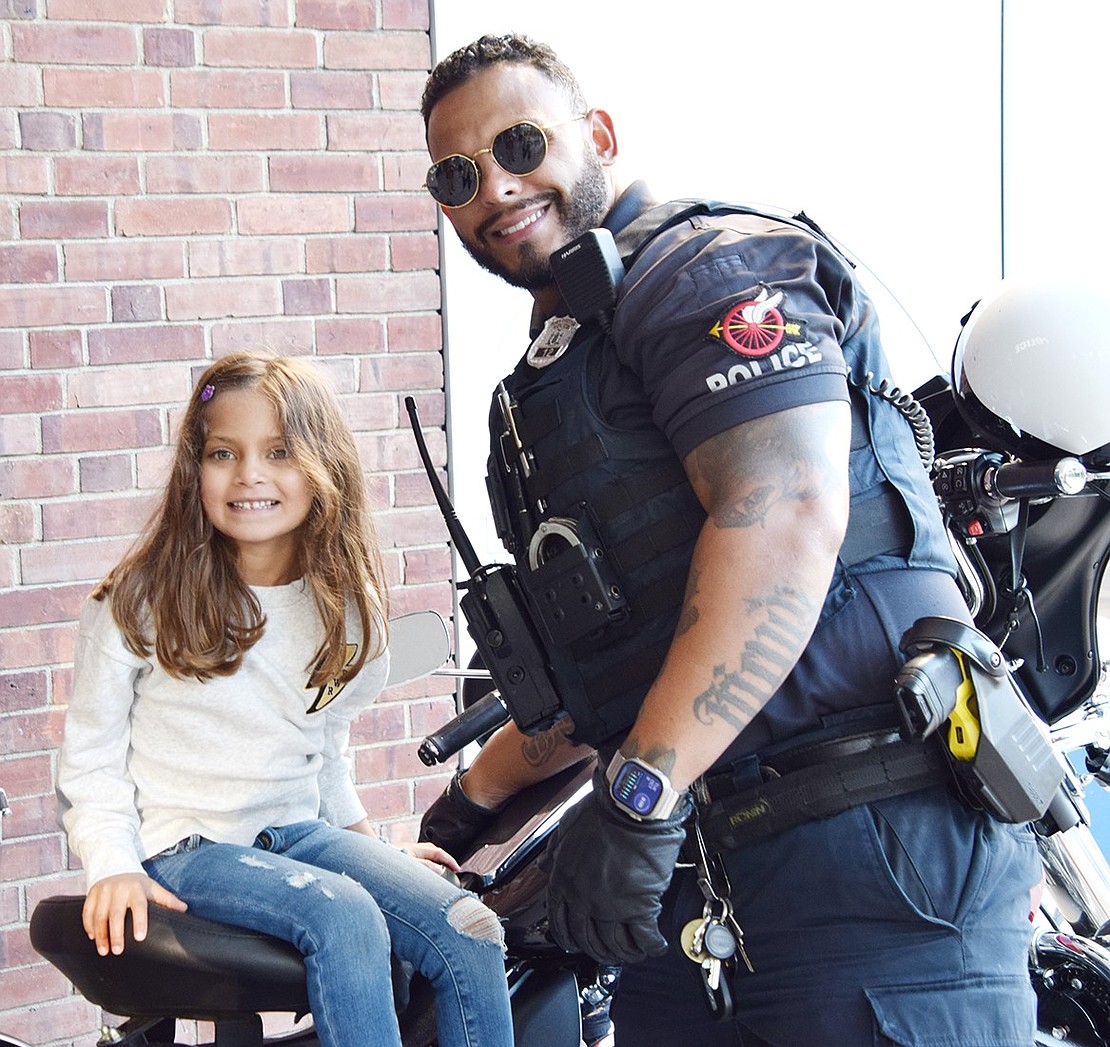 Sitting atop a Port Chester police motorcycle outside of King Street School, 5-year-old Munson Street resident Nieve Damle smiles for the camera with Officer David Arroyo.