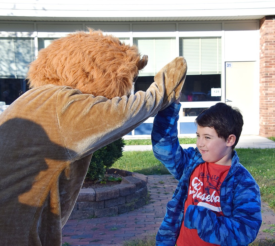 King Street School mascot Roary the Lion, played by Port Chester High School senior José Carillo, high fives 6-year-old Harrison Burt of Mitchell Place.