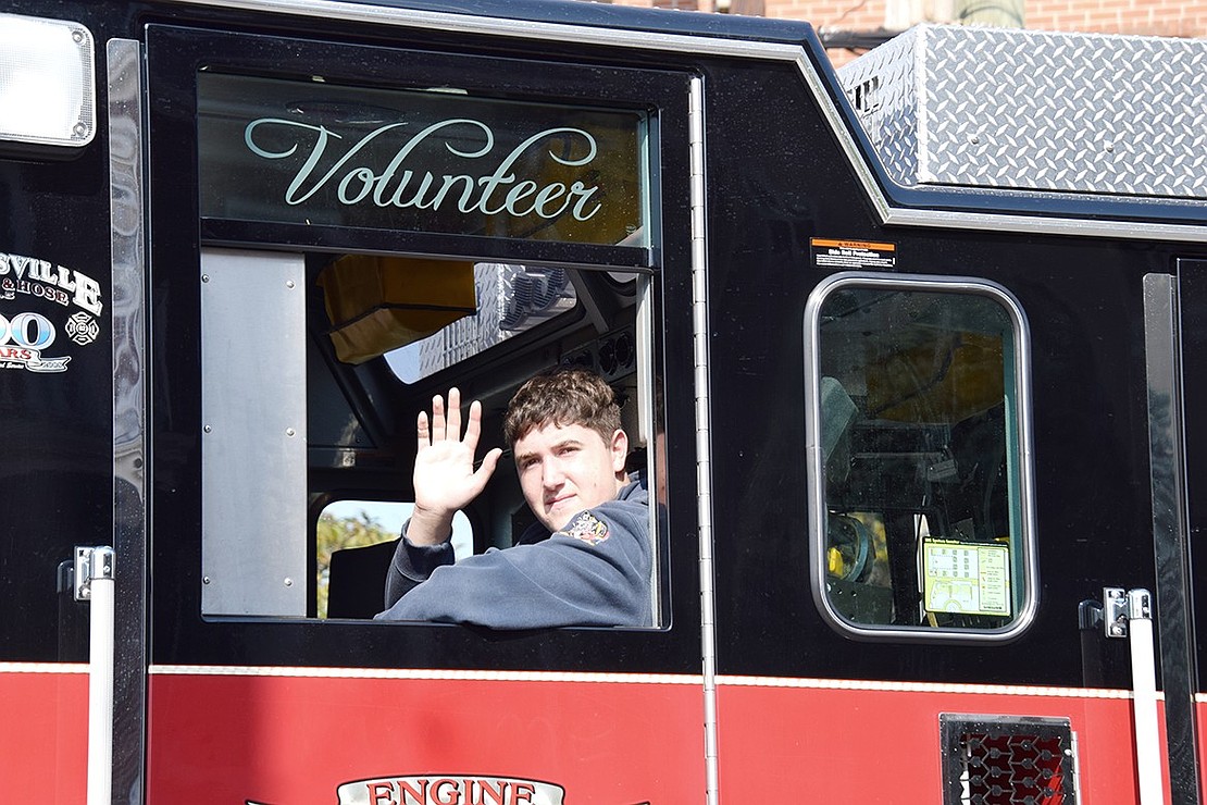 Port Chester volunteer firefighter Joe Cicerello waves from his seat on the Brooksville Engine & Hose Co. 5 truck.