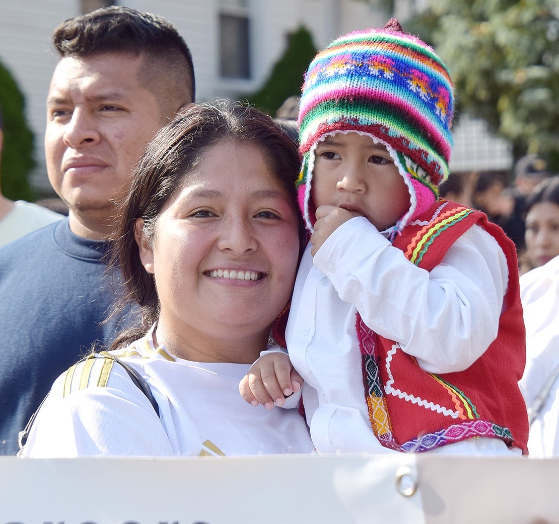 Central Avenue resident Alanis Mendoza and her 3-year-old son Ian Castillo peek over a banner as they march with the Family Services of Westchester.