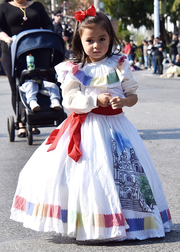 Mia Escobar, a 3-year-old who lives on Bent Avenue, takes a wary look at the camera while pausing for a break during the annual Columbus Day Parade on Sunday, Oct. 13