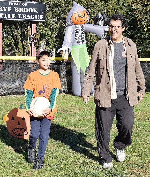 Marco Colmenares proudly walks with his father Jeames to pay for his perfect white pumpkin. The Ridge Street School fourth-grader used his own money that he earned as a street performer in Central Park.