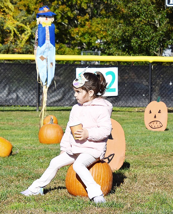 Candy Lane resident Livia Schalik, 4, rests on a pumpkin while nursing her cup of hot chocolate.