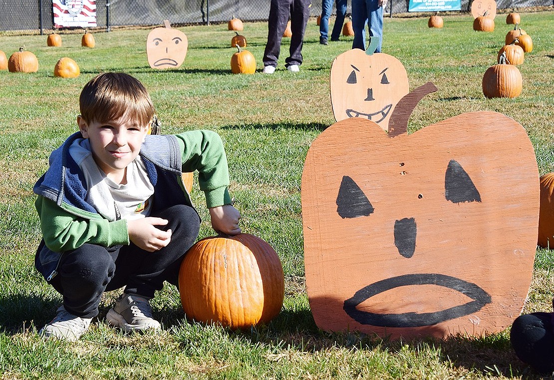 Levi Nesser, a 6-year-old resident of The Arbors, poses for a photo with some of the real and fake gourds set up around the baseball field.