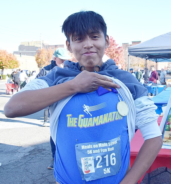 Grove Street resident Kevin Guaman, 20, lifts his sweatshirt to show off his custom “Guamanator” shirt and medal he earned for finishing the 5K & Fun Run first in his division.