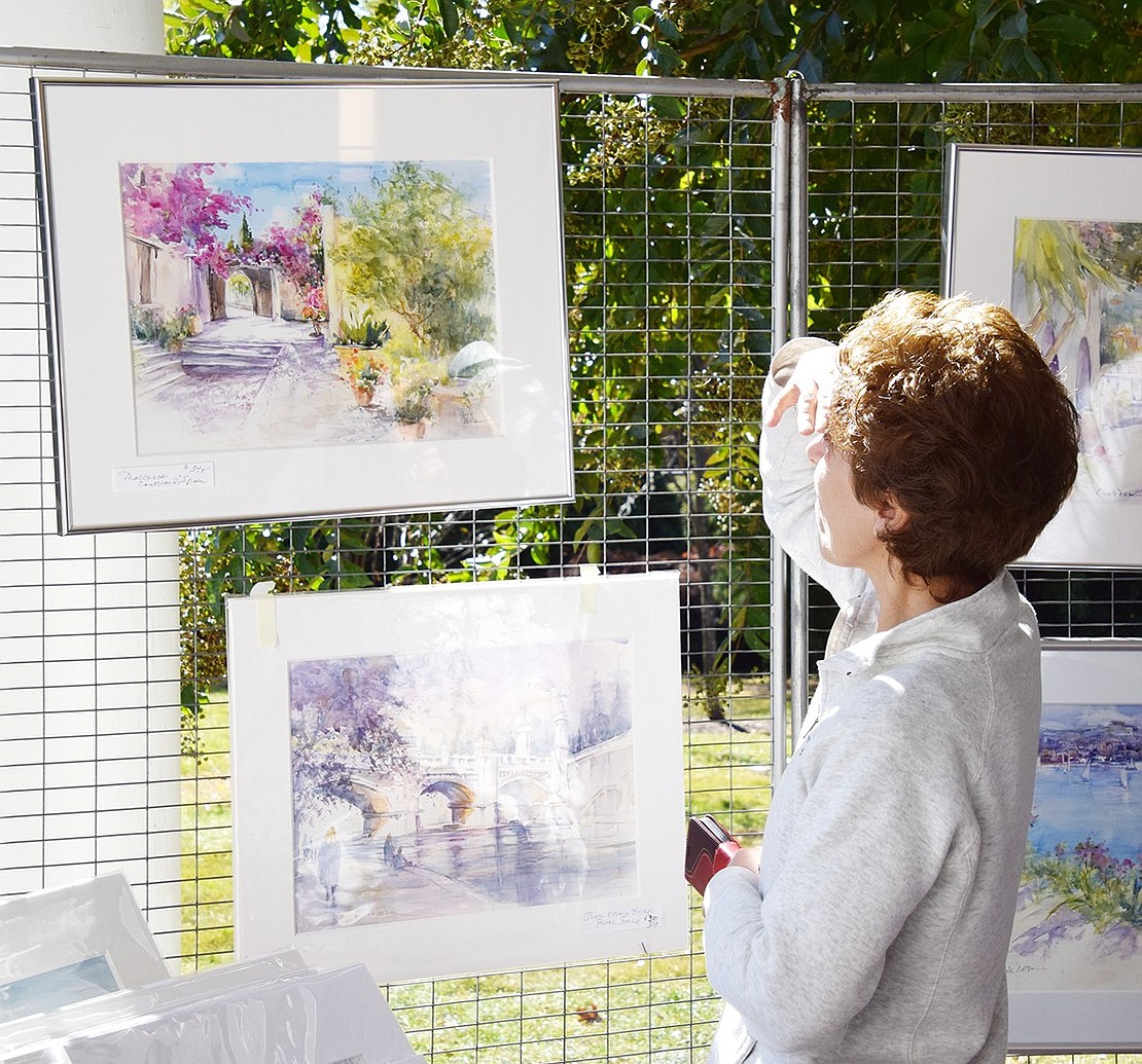 Port Chester resident Hristina Galabova protects her eyes from the sun while admiring pieces by Greenwich-based painter Carole Nelson.