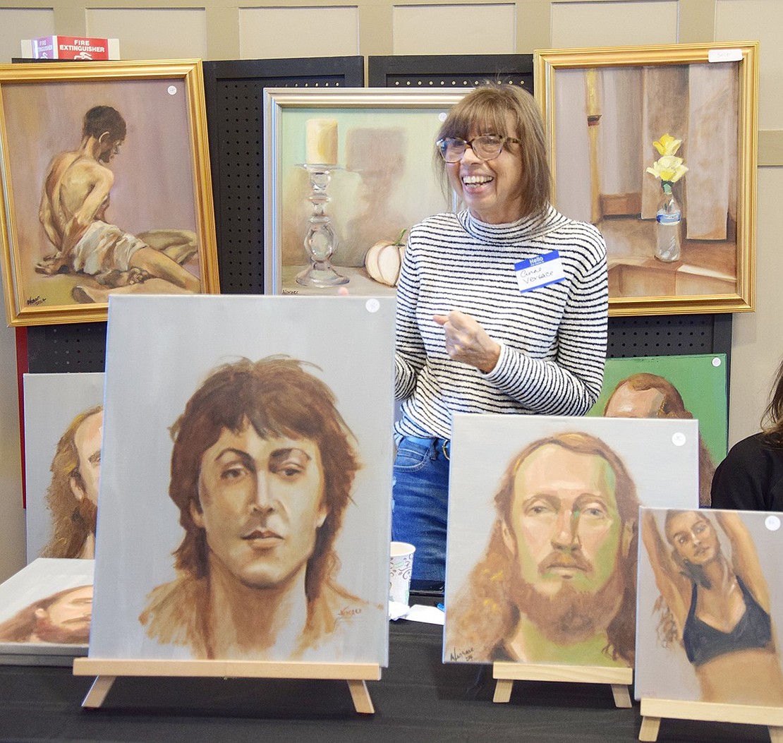 Anne Versace, an artist who lives in Port Chester, laughs from her table at the exhibition.