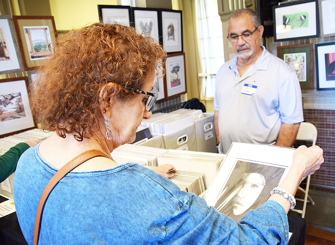 Callie Kulakis, a Davenport Avenue resident, flips through the works of Yonkers artist Steve Rossi.