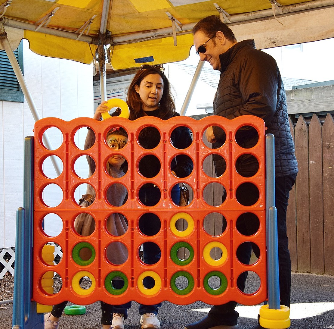 Elsa Azimaraghi, a kindergartner at Ridge Street School, makes her move during a match of Connect Four against her dad, Omid, as Noushin Khazaei of New Rochelle watches.