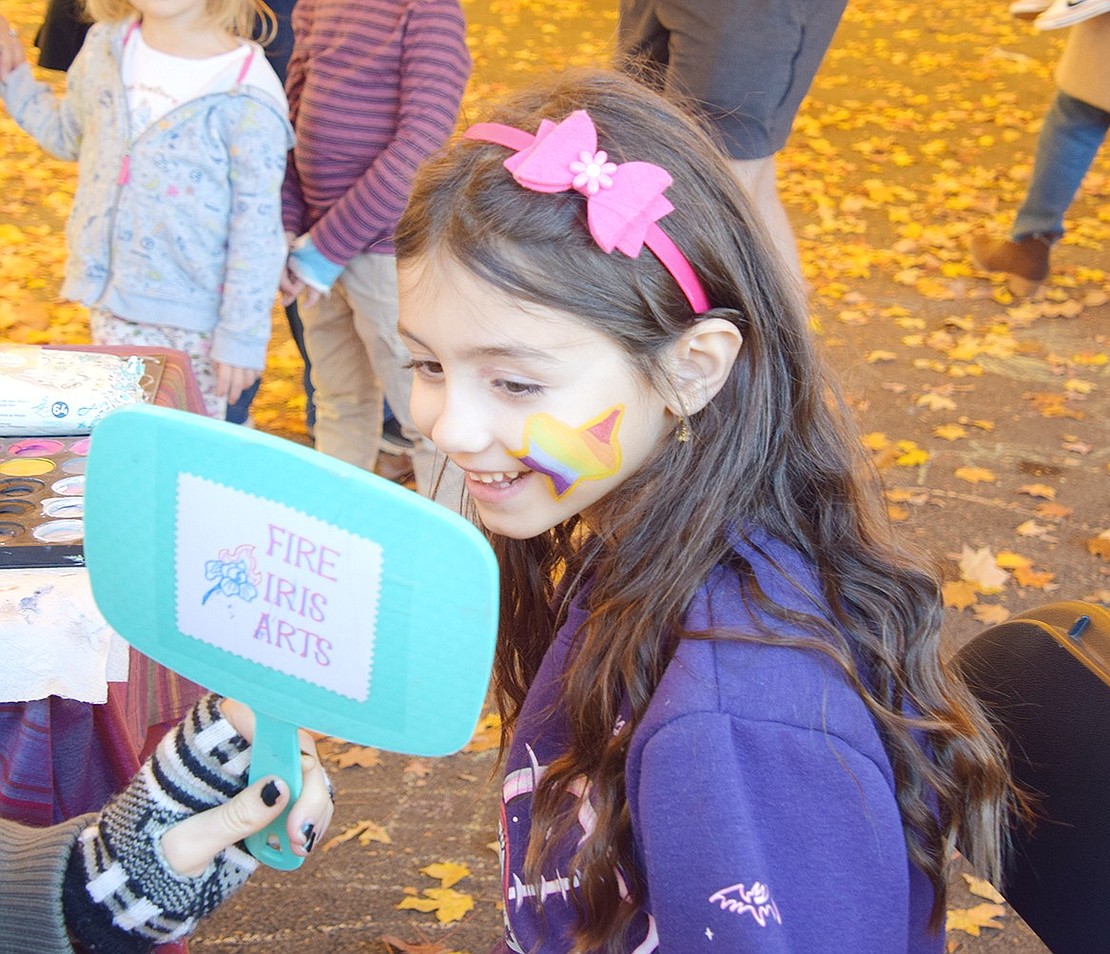 Arlington Place resident Mersana Zangbar, a second-grader at Ridge Street School, smiles widely after seeing the colorful star painted on her face.