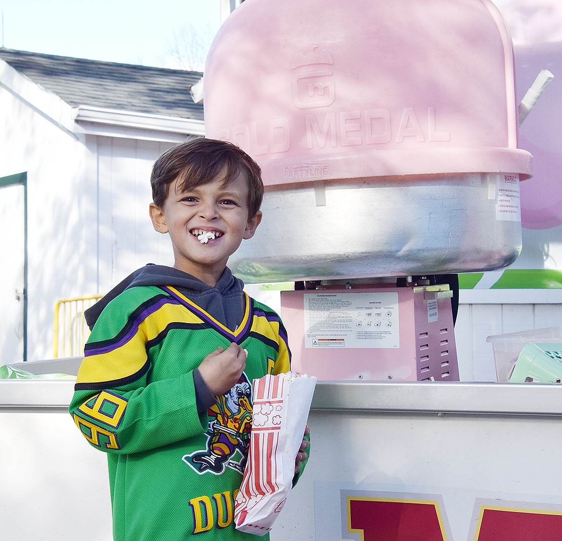 Cameron Davidson, a 6-year-old who lives on Eagles Bluff, smiles with a piece of popcorn in his mouth while waiting for some cotton candy.