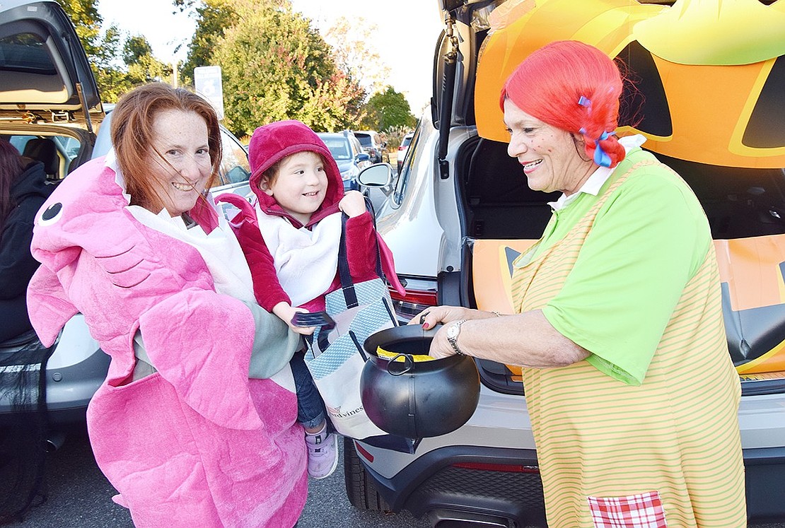 Rye Brook native Jessica Albalah (left) holds up her 2-year-old daughter Jillian Griffel to pick out some treats from Pippi Longstocking, also known as Rye Town Clerk Hope Vespia.