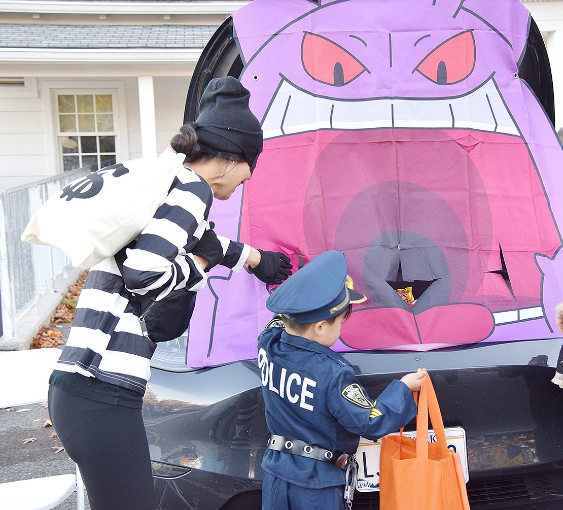 Rye resident Sandra Pelio helps her 3-year-old son Cameron reach into the maw of the spooky ghost Pokémon Gengar to snag a snack.