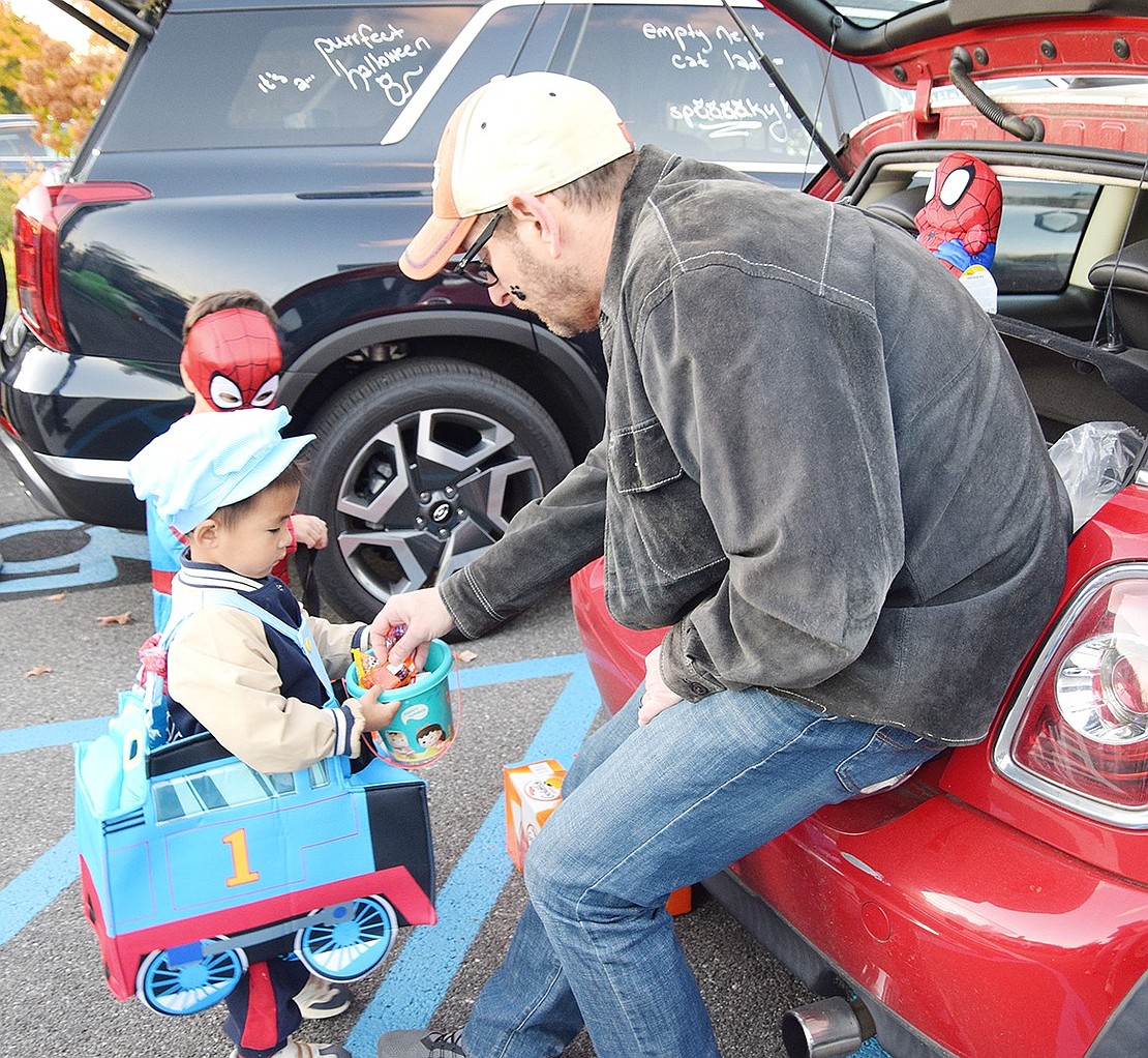 Miles Wu, a 3-year-old Talcott Road resident dressed as Thomas the Tank Engine, receives candy from former Blind Brook Board of Education Trustee Scott Jaffee at the annual Rye Town Trunk-or-Treat at Crawford Park on Saturday, Oct. 26. Hundreds of people stopped by in their Halloween costumes to grab sugary treats.