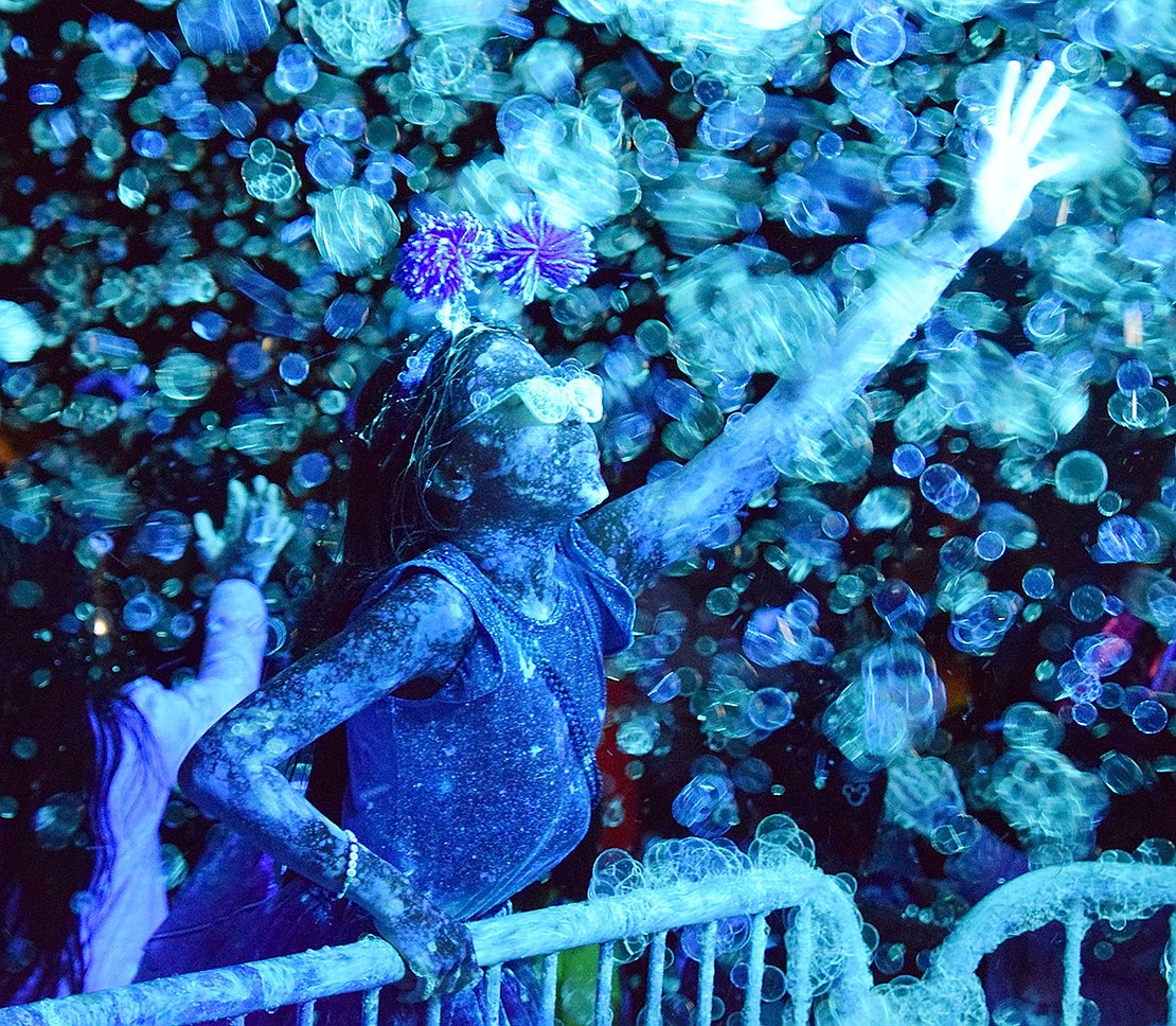 Glowing under blacklights while getting blasted by neon foam, Antonella Olivares, a Greenwich, Conn., resident who lives within blocks of Lyon Park, reaches over a rail to play with bubbles spouting from a bus during Port Chester’s Halloween in the Park event on Monday, Oct. 28.