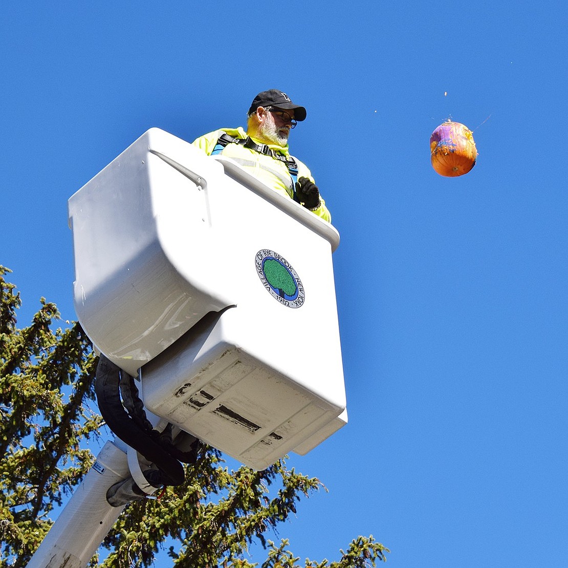 Rye Brook Department of Public Works (DPW) employee Mark Goldstein releases a jack-o’-lantern from approximately 50 feet in the air. According to DPW Foreman Paul Vinci, the crew drew straws to determine who would smash pumpkins from the bucket of the cherry picker.