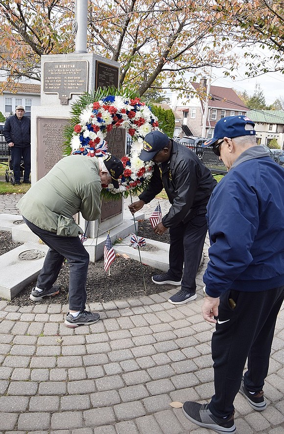 Port Chester Vietnam veterans Dominick Mancuso (U.S. Army) and Fred Griffin (U.S. Coast Guard) place a memorial wreath at the flagpole monument recognizing local veterans who died during World War II and the Korean War, with a special memorial for the 8 Willow Street Boys who gave their lives in WWII. Looking on is Vietnam vet Pat Barrese of North Regent Street.