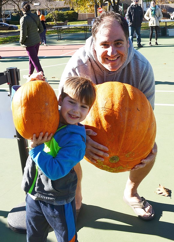 Old Orchard Road resident Eric Hammer holds up the 50-pound pumpkin he brought to be destroyed. His four-year-old son Matthew poses in front of him with a much smaller gourd.