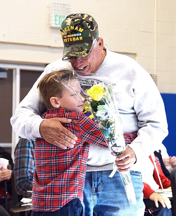 King Street School student Aiden Barrow, 7, hugs New Jersey-based Vietnam War veteran John Mack during the school’s annual Veterans Day ceremony on Friday, Nov. 8, where students presented soldiers with roses to thank them for their service. While the two aren’t related, Mack became a member of the Barrow family through their participation in the Hudson Valley Honor Flight.