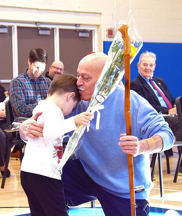 While giving out his rose, King Street Elementary School kindergartner Ryan Burke gets a hug and a kiss from his assigned veteran Doug Schwartz at the school’s annual Veterans Day ceremony on Friday, Nov. 8.