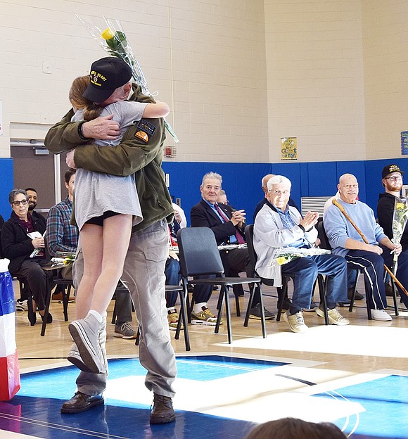 Rob Somerville, a Vietnam War veteran who lives in Harrison, lifts his 9-year-old granddaughter Piper McLoughlin after she handed him a rose to thank him for his service.