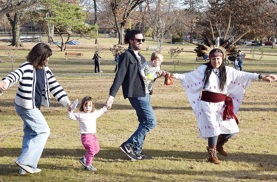 Port Chester resident Whitney Clearwater (left) and her 3-year-old daughter Amelia, husband Jason and 1-year-old son Ansel hold hands with Aztec Dancer Lily Rojas as they partake in a friendship dance.