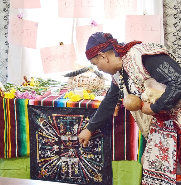 Sosimo Nolasco, a member of La Santa Cruz del Caminante from Queens, describes a visual representation of the Aztec Book of Life displayed on an ofrenda, an offering shrine used during Dia de Los Muertos.