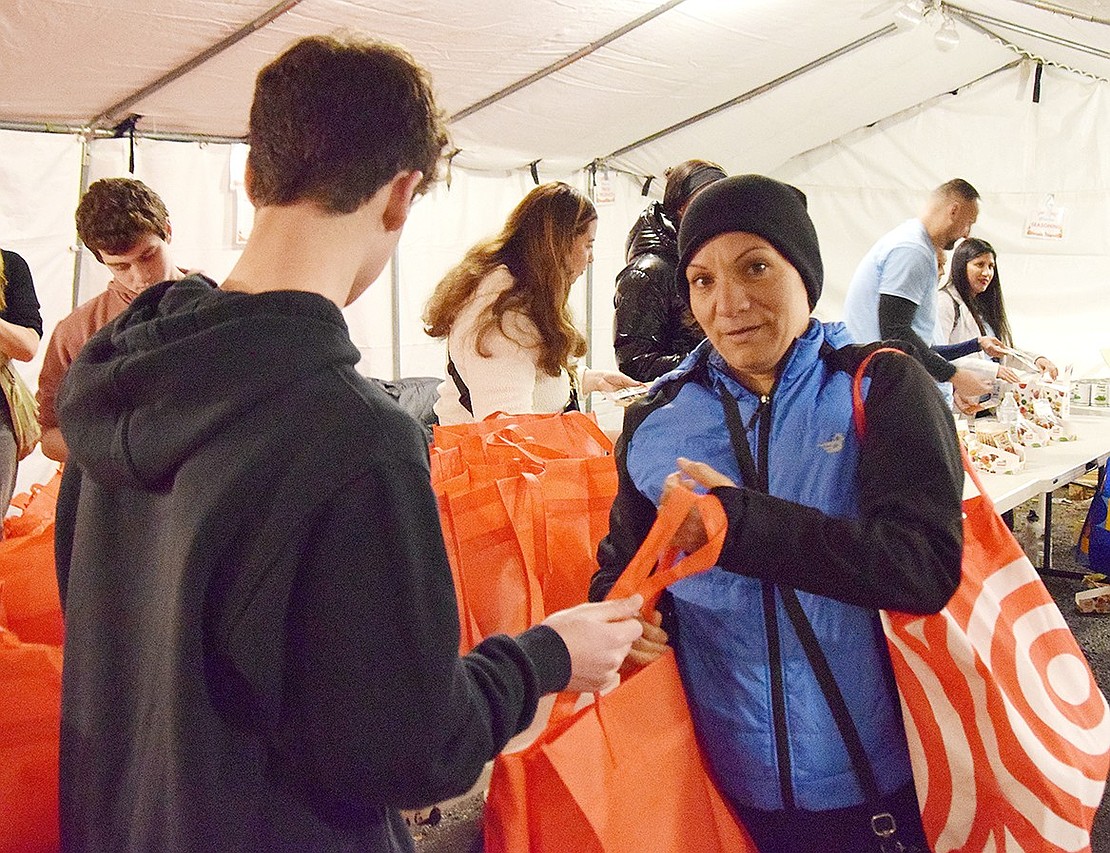 Blind Brook High School junior Jake Messafi hands off a 5-pound bag of fall greens to Rye Brook resident Martha Licea.