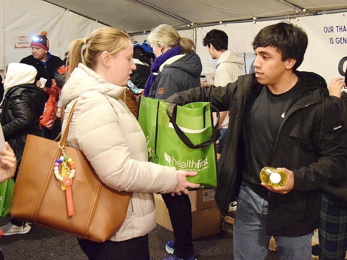 Ellendale Avenue resident Linda Petrilli accepts some cooking oil from Port Chester High School junior Rodrigo Gonzales at the Carver Center’s annual Thanksgiving Distribution on Thursday, Nov. 21. Employees and volunteers worked quickly to give away 69,600 lbs. of food before the holiday.