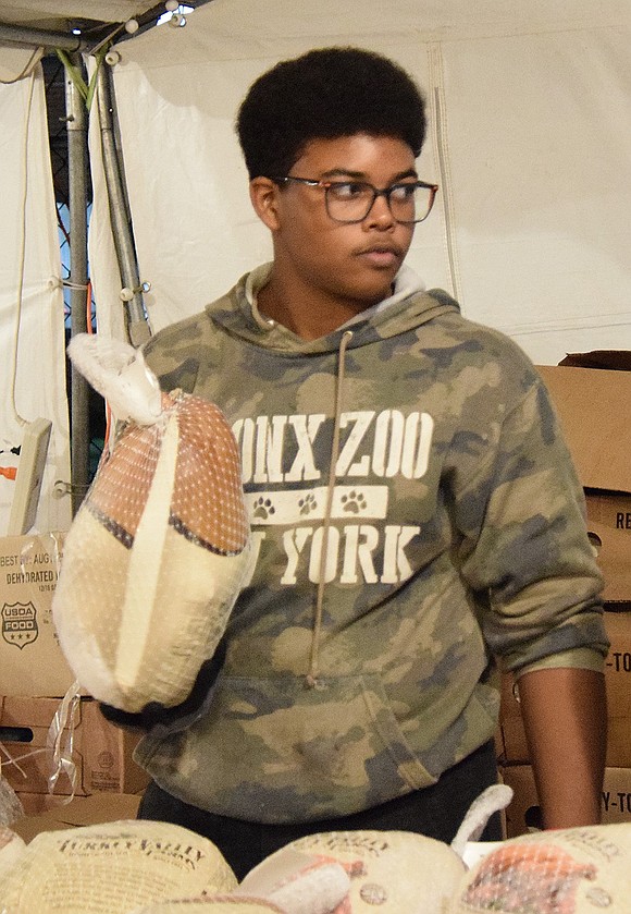 Port Chester High School sophomore Ezekial Sena shows off his strength by holding up a turkey as he waits for the next wave of attendees.