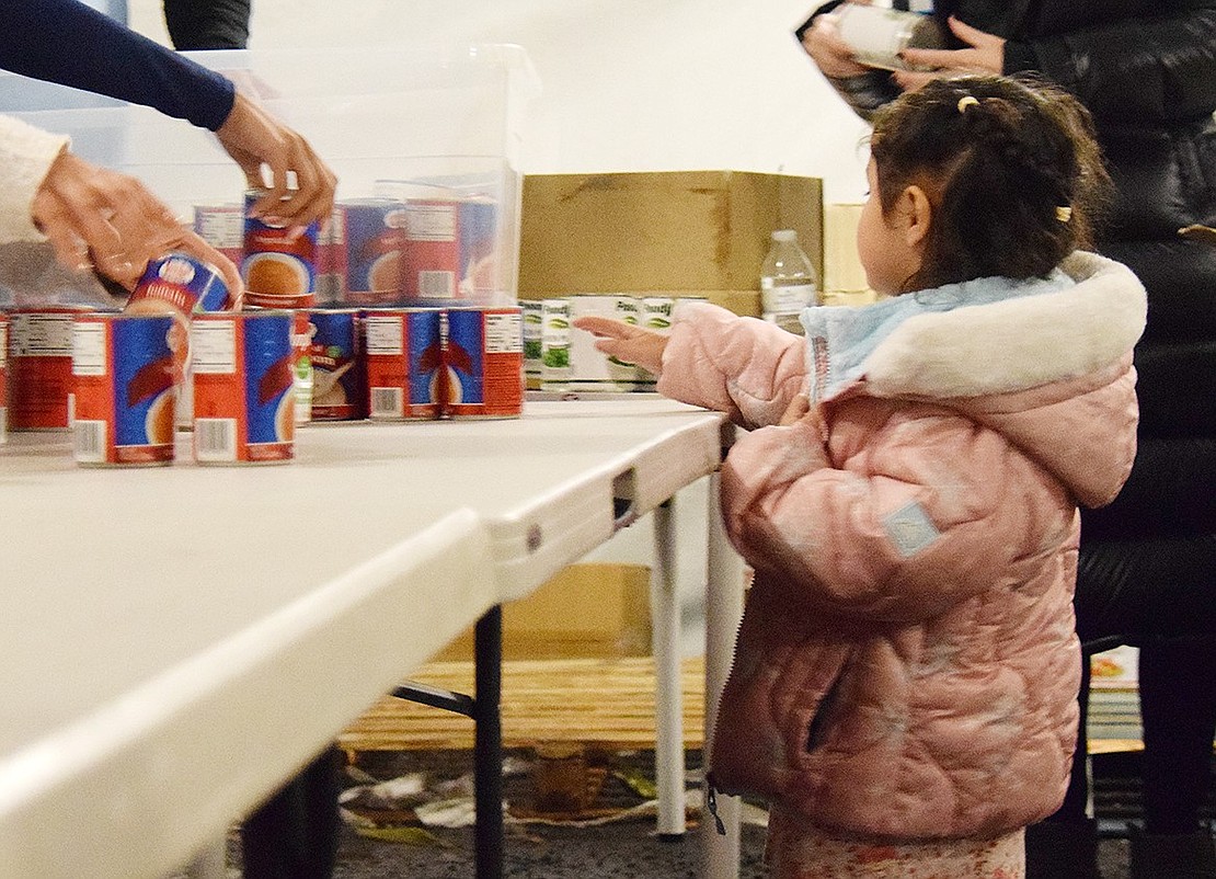 New Rochelle resident Astana Olano takes a gander at some of the canned soups being distributed.