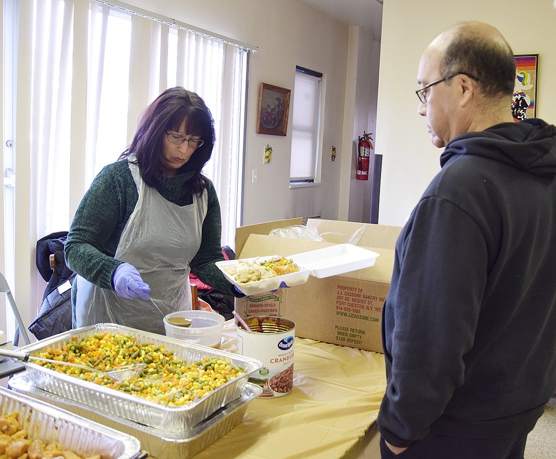 Christine Keller of Pelham adds gravy to Terrace Avenue resident Jesus Tagle’s Thanksgiving dinner.