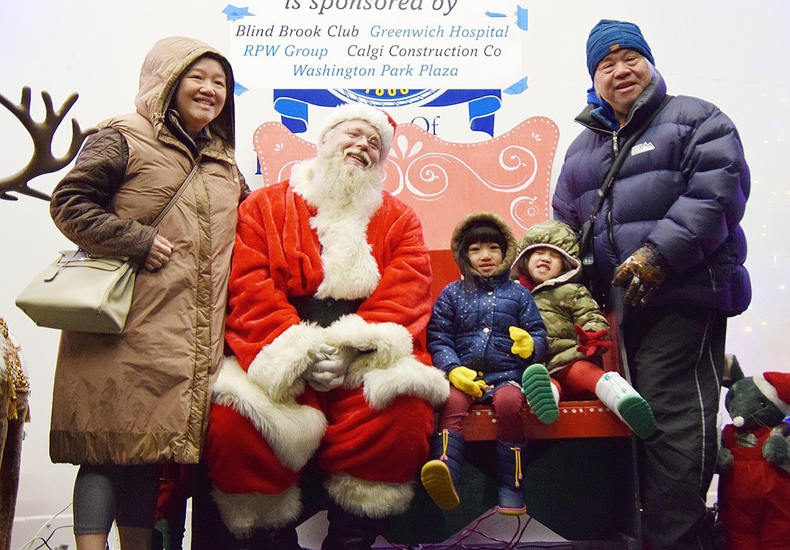 Valley Terrace residents Stephanie and Howard Lim, Jr., (standing) pose for a photo with Santa Claus (played by Chris Paluili of Chris and Pete Amusements) and twin 3-year-old granddaughters Julie and Evie Lim.