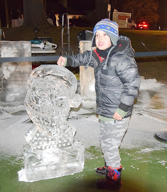 Nicolas Mendes, a first-grader at Ridge Street Elementary School, confirms the sculpture of Santa Claus is made of ice by testing its feel.