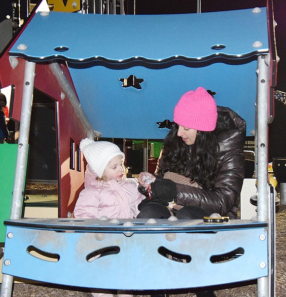 Taking a break from the crowd, Bellefair Boulevard residents Ashley Kumf and her 2-year-old daughter Avery eat some snacks under the cover of some playground equipment.