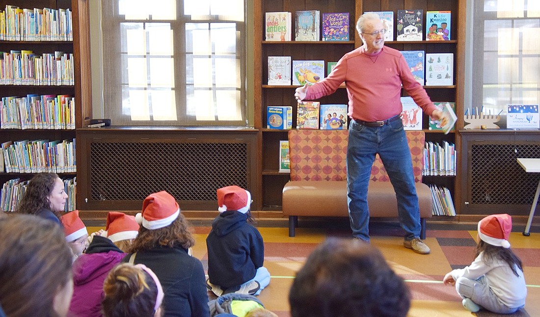 Port Chester Trustee Joe Carvin paces and gestures around the room as he reads the Spanish translation of “The Grumpy Reindeer” by Clare Wilson at the Bilingual Story Time event hosted by the Port Chester Hispanic Advisory Board at the Port Chester-Rye Brook Public Library on Saturday, Dec. 7.