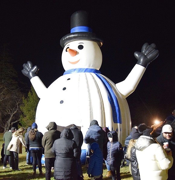 Dozens of children and their families line up for a turn in the snowman-shaped bounce house set up behind the Crawford Mansion Community Center.